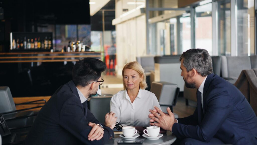 Business professionals engaged in a meeting at a café setting, discussing ideas.