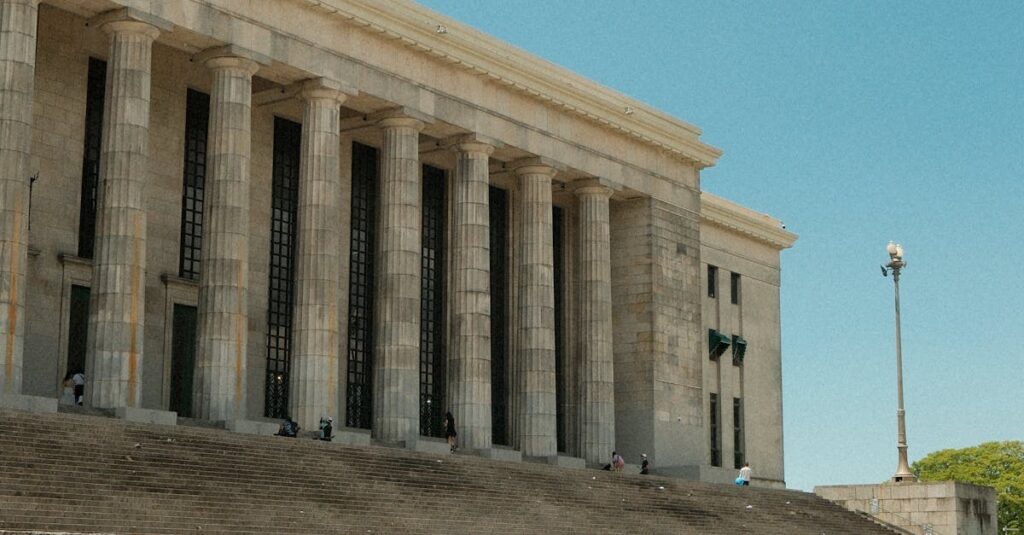 A grand neoclassical building featuring pillars under a bright blue sky.